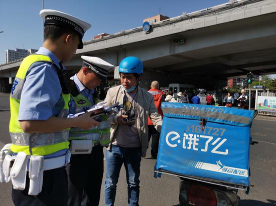 在海淀五棵松路口，民警查扣到了一辆未按规定悬挂临牌的外卖电动车。新京报记者 王贵彬 摄